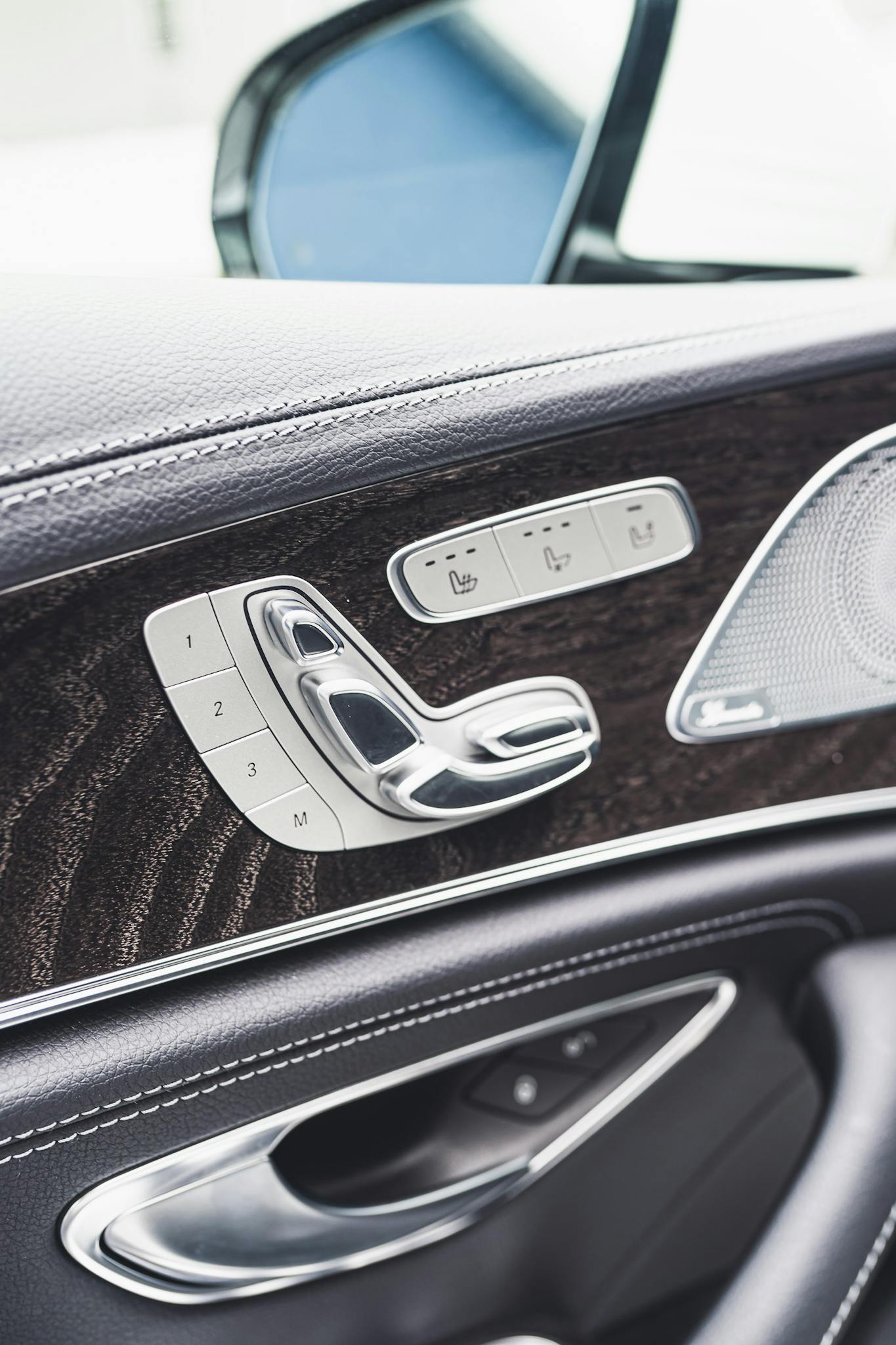 Detailed view of a luxury car's interior door panel with sleek metal controls.