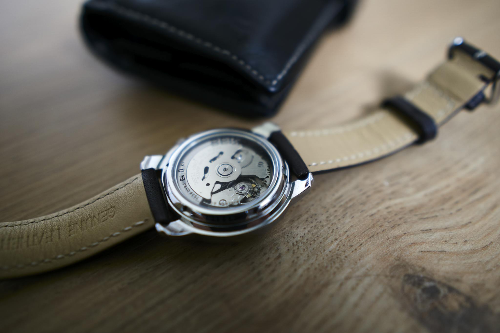 Detailed view of a mechanical wristwatch with leather strap on a wooden table.